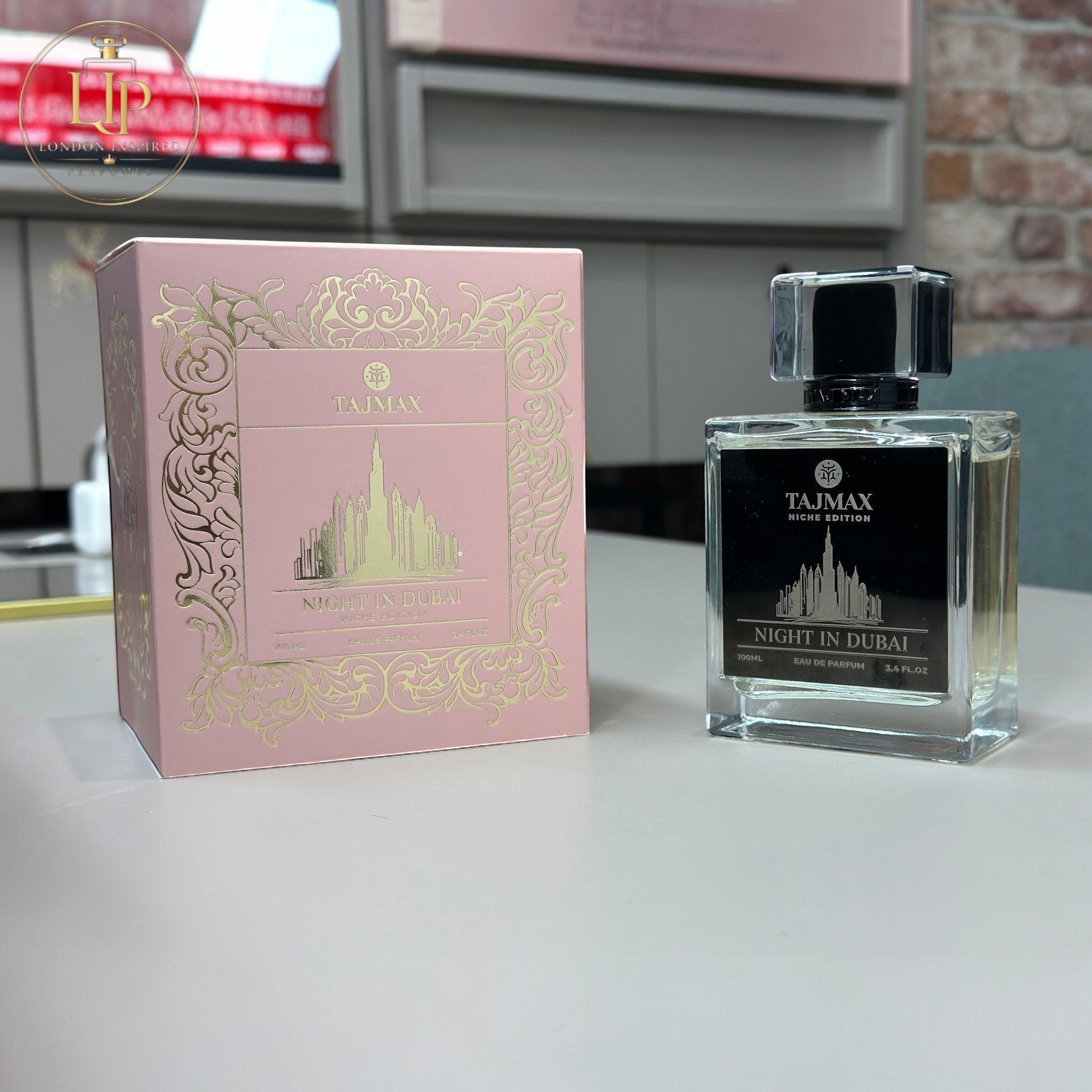 Perfume bottle and packaging with 'Tajmax' branding on a kitchen counter.
